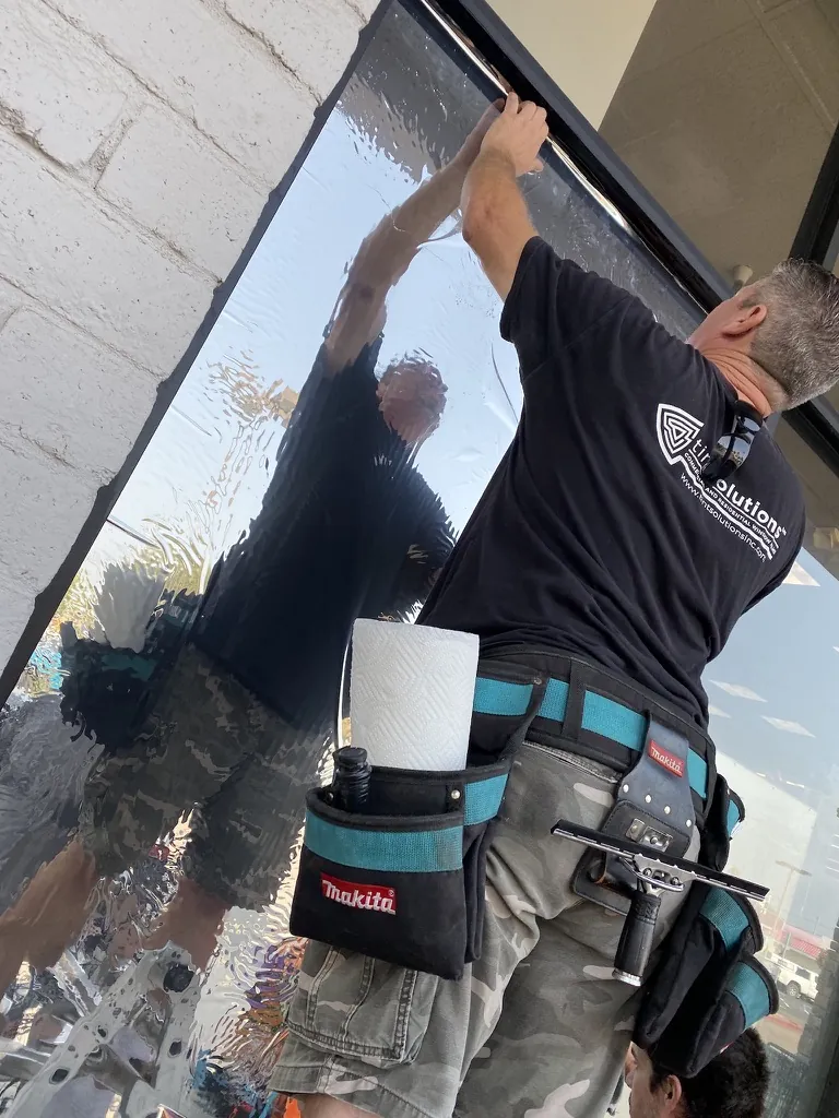 Tint Solutions installer applying film to a commercial storefront