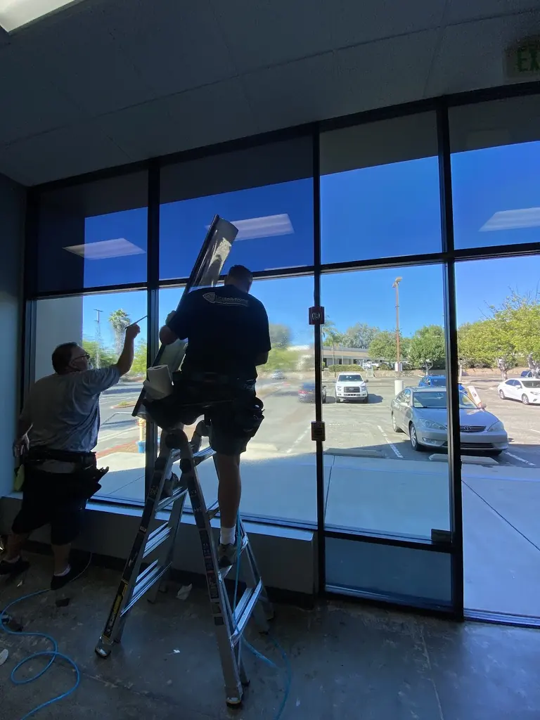 Tint Solutions installers applying commercial window film to a tall office window wall