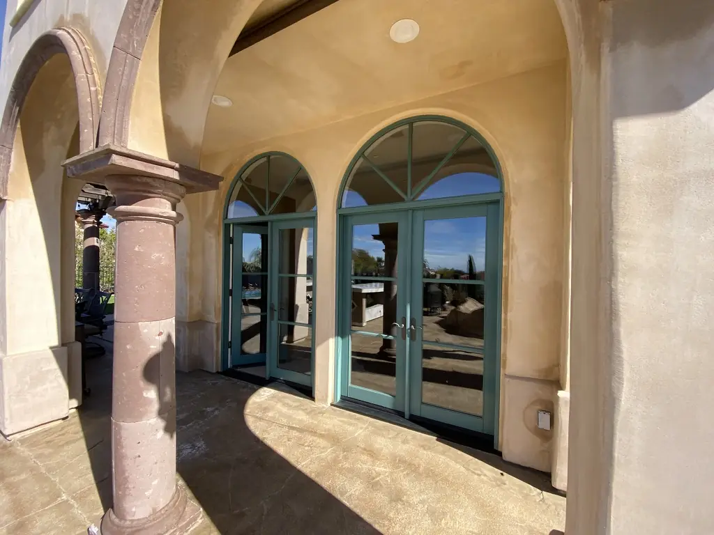 Arched French doors under a loggia on a Spanish-style estate, with window film by Tint Solutions