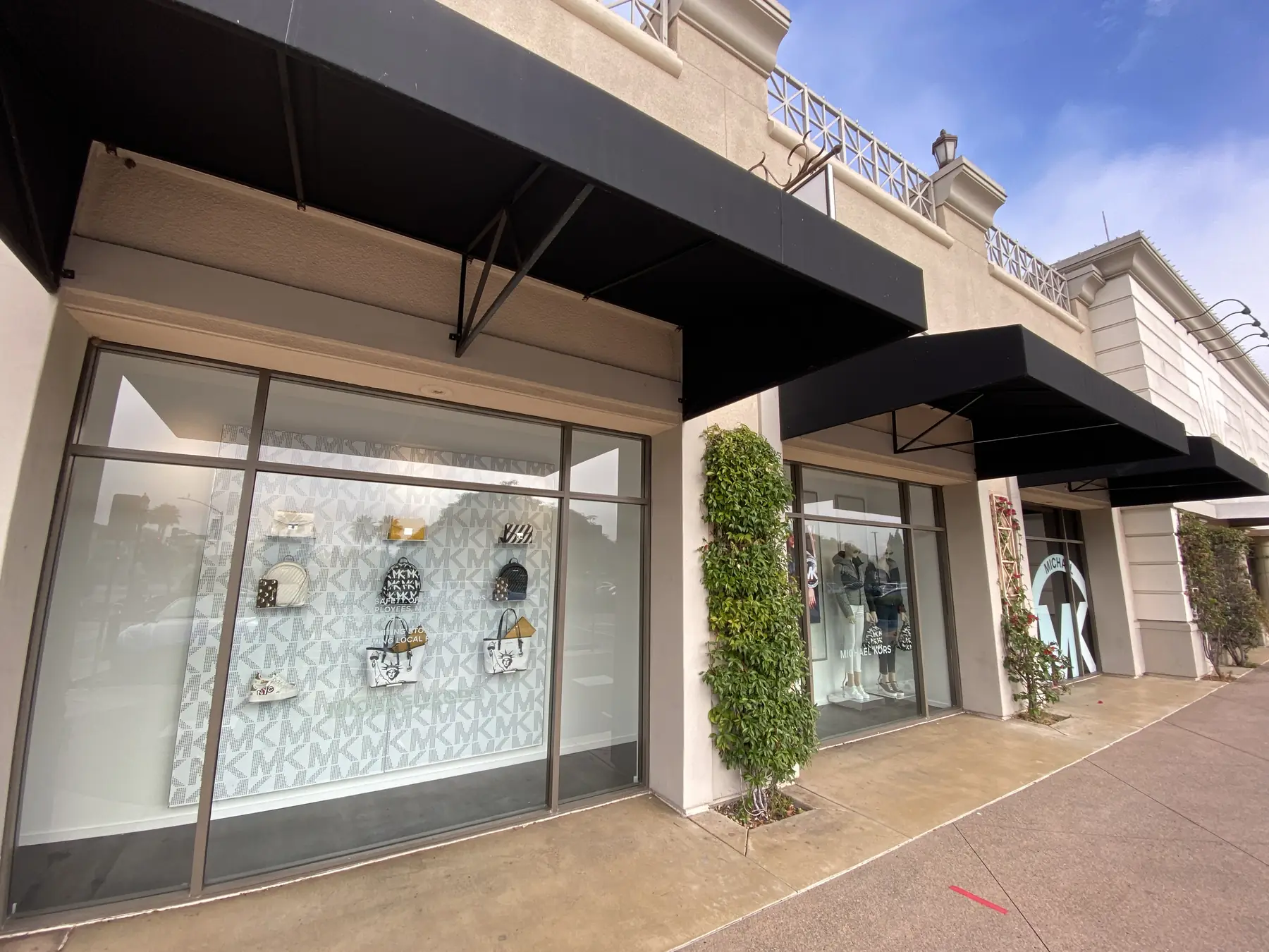 Storefront windows under black awnings with security film