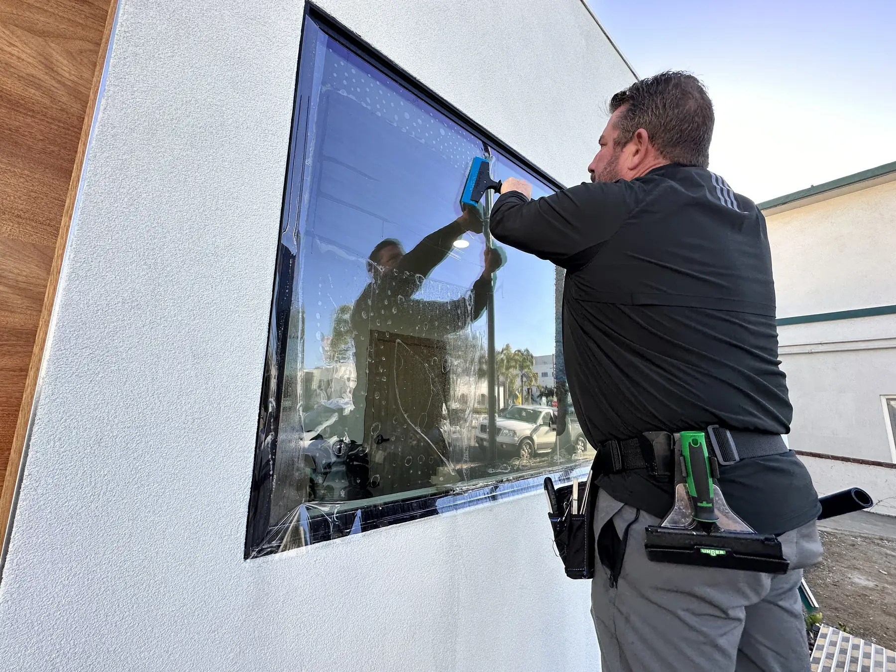 Installer squeegeeing security film onto an exterior window