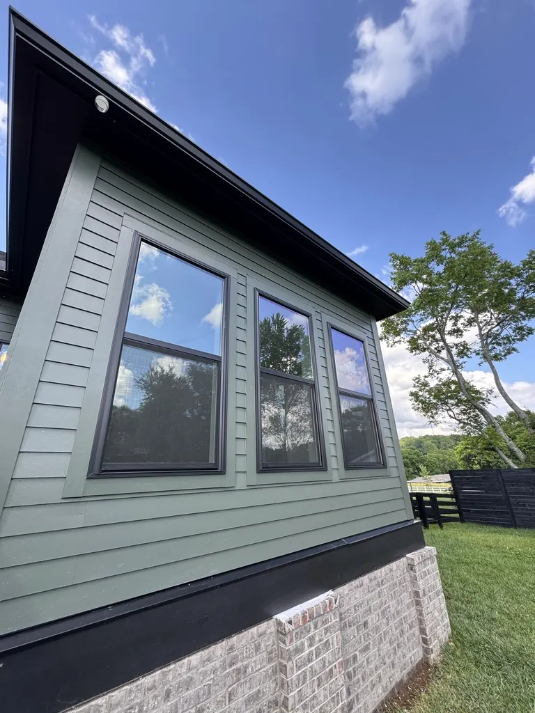 Three tall windows with window film on a green-sided Middle Tennessee home