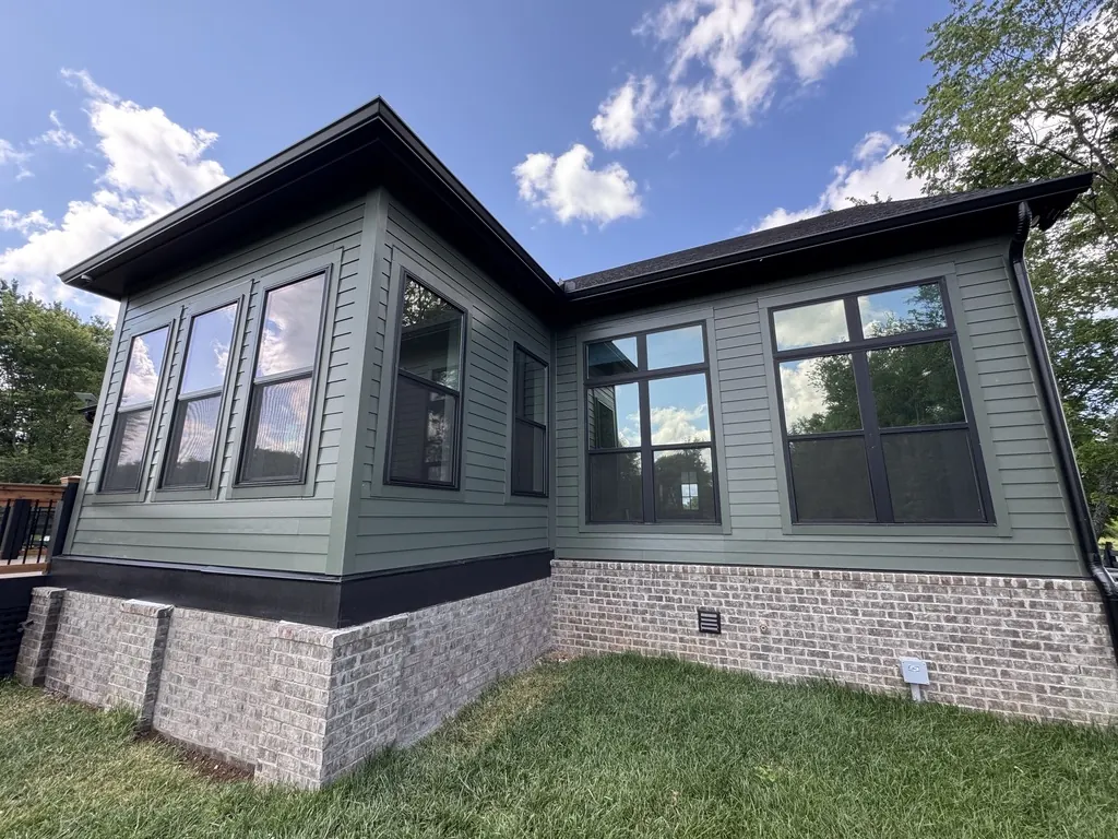 Green-sided Middle Tennessee home with dark-framed sunroom windows